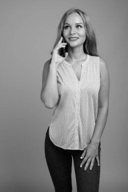 Stüdyoda, sarı saçlı güzel bir iş kadınının siyah beyaz arka planda gri bir görüntüsü var.