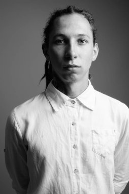 Siyah-beyaz gri arka planda rastalı genç iş adamının stüdyo fotoğrafı.