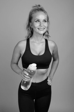 Stüdyoda, sarı saçlı, gri arka planda siyah beyaz spor salonuna hazır güzel bir kadın var.