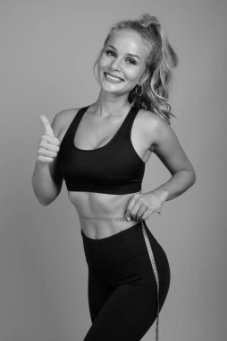 Stüdyoda, sarı saçlı, gri arka planda siyah beyaz spor salonuna hazır güzel bir kadın var.