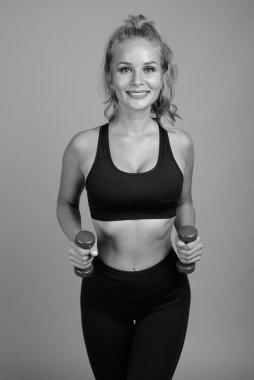 Stüdyoda, sarı saçlı, gri arka planda siyah beyaz spor salonuna hazır güzel bir kadın var.