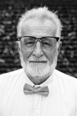 Siyah beyaz Bangkok 'u gezerken şık kıyafetler giyen yakışıklı sakallı yaşlı turistin portresi.