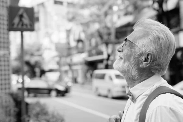 Красивий бородатий старший турист досліджує місто в чорно-білому — стокове фото