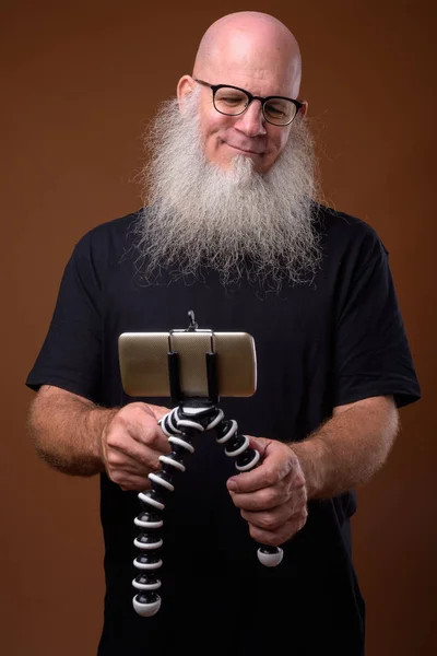 Rijpe kale man met lange grijze baard tegen bruine achtergrond — Stockfoto