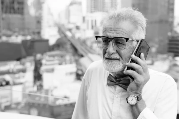 Knappe bebaarde senior toerist die de stad verkent in zwart-wit — Stockfoto