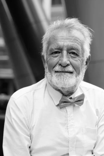 Красивий бородатий старший турист досліджує місто в чорно-білому — стокове фото