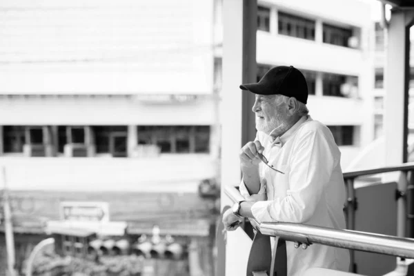 Красивый бородатый старший турист исследует город в черно-белом — стоковое фото