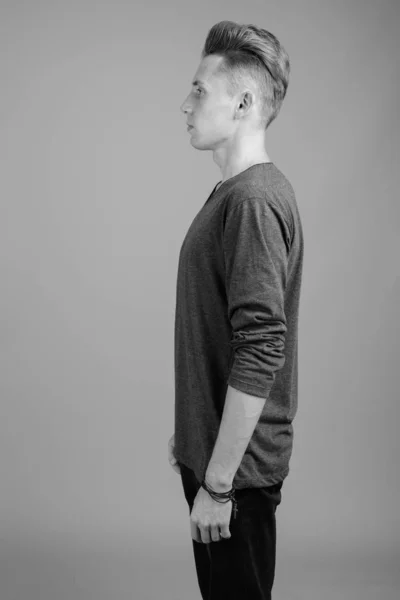 Portrait of young man against gray background in black and white — Stock Photo, Image