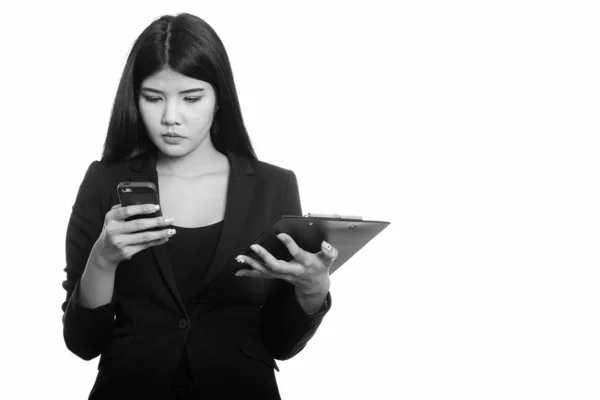 Studio colpo di giovane donna d'affari asiatica utilizzando il telefono cellulare tenendo appunti — Foto Stock