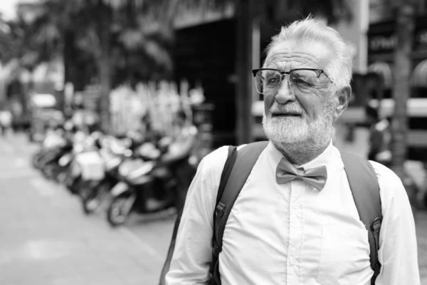 Pohledný vousatý starší turista objevující město v černé a bílé — Stock fotografie