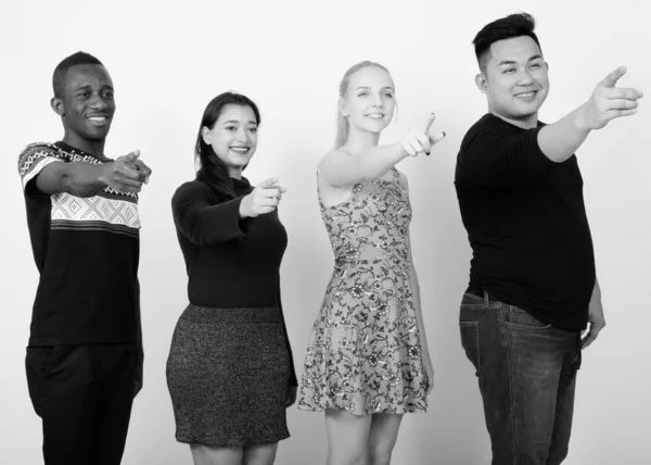 Studio shot di felice gruppo eterogeneo di amici multietnici sorridenti e pensanti mentre puntano a distanza insieme — Foto Stock