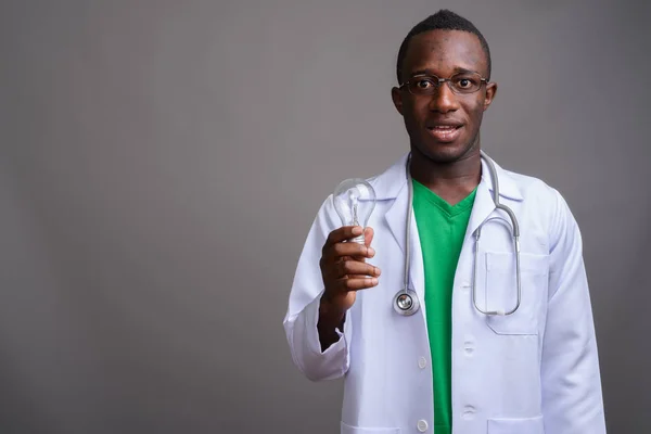 Jovem médico homem africano vestindo óculos contra backgro cinza — Fotografia de Stock