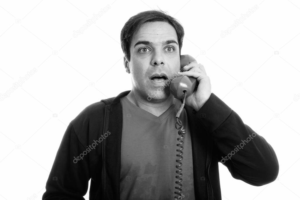 Close up of thoughtful young Persian man talking on old telephone while looking shocked