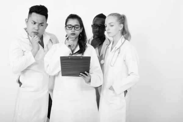 Studio skott av mångskiftande grupp av multi etniska läkare tänkande medan läsning på Urklipp tillsammans — Stockfoto