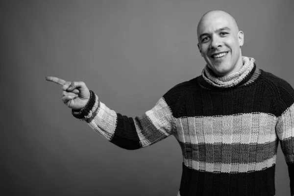 Handsome bald man against gray background in black and white