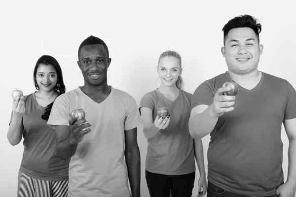 Studio shot van gelukkig diverse groep van etnische vrienden multi glimlachen terwijl het geven van rode appel samen — Stockfoto