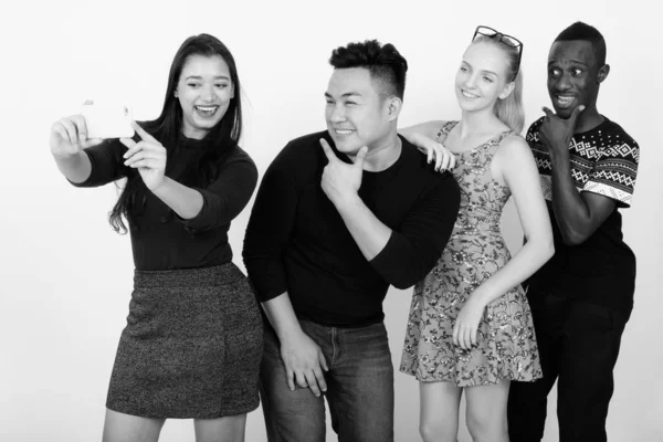 Studio shot of happy diverse group of multi ethnic friends souriant et posant tout en prenant des photos selfie avec téléphone portable ensemble — Photo