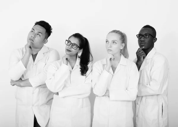Studio shot de divers groupes de médecins multi-ethniques pensant tout en levant les yeux ensemble — Photo