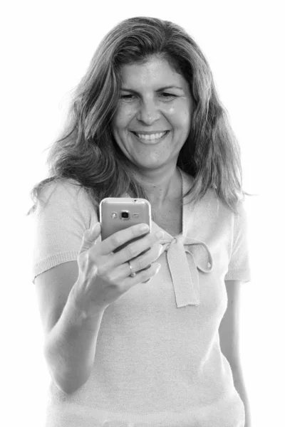 휴대 전화를 사용 하는 동안 웃 고 성숙한 행복 한 여자의 스튜디오 샷 — 스톡 사진