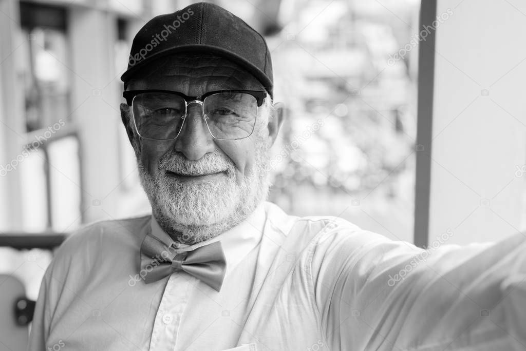 Handsome bearded senior tourist man exploring the city in black and white