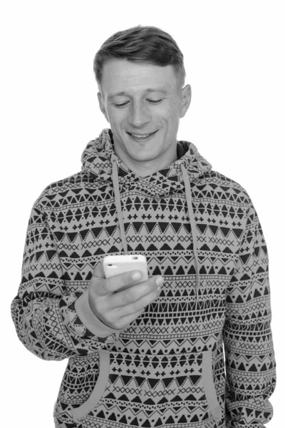 Studio shot of young happy Caucasian man using mobile phone isolated against white background — Stock Photo, Image