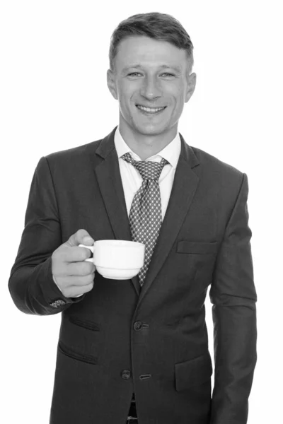 Studio shot van jonge gelukkig Kaukasische zakenman koffiekopje geïsoleerd tegen de witte achtergrond te houden — Stockfoto