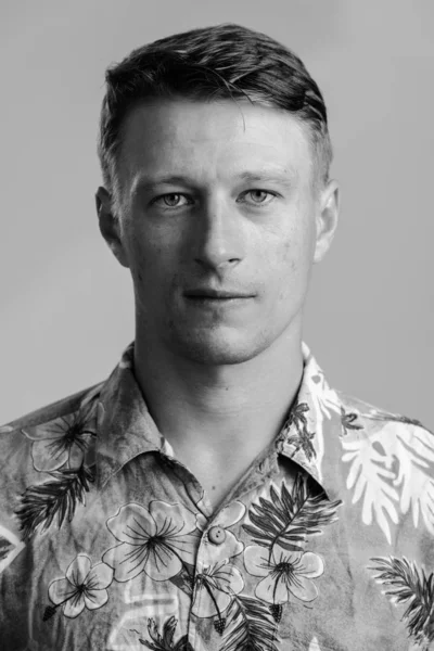 Porträtt skott av ung stilig kaukasiska man i Hawaii skjorta isolerade mot grå tonad bakgrund — Stockfoto