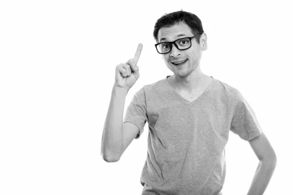 Studio shot of happy young man smiling with eyeglasses while pointing finger up — Stock Photo, Image