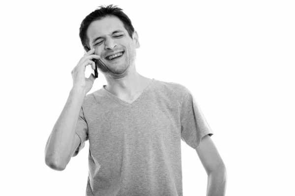Studio záběr šťastný mladý muž usmívá a směje se při rozhovoru mobilním telefonu se zavřenýma očima — Stock fotografie