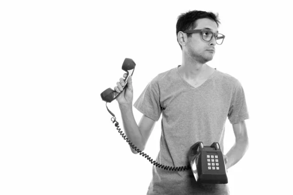 Estudio de un joven sosteniendo un viejo teléfono y mirando hacia otro lado — Foto de Stock