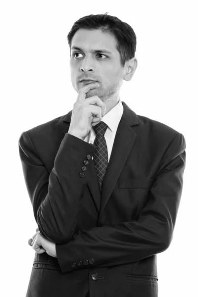 Studio shot of young businessman thinking while looking at distance — Stock Photo, Image