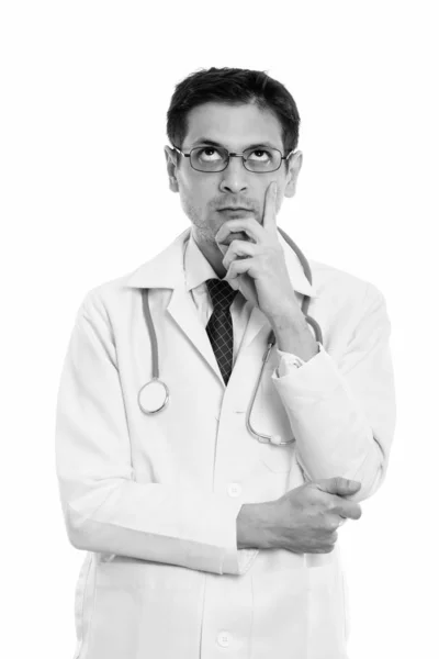 Studio shot de jeune homme médecin portant des lunettes tout en pensant et en levant les yeux — Photo