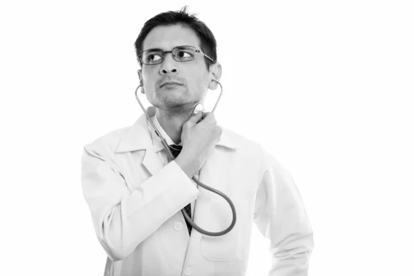 Studio shot de jeune homme médecin en utilisant stéthoscope sur le cou tout en pensant — Photo