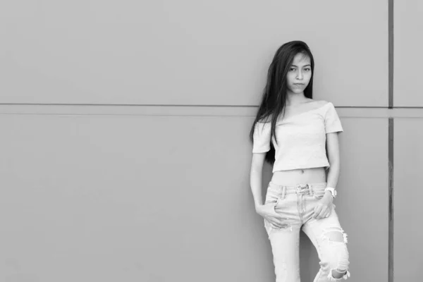 Joven hermosa asiática adolescente posando y apoyándose contra la pared de hormigón al aire libre —  Fotos de Stock