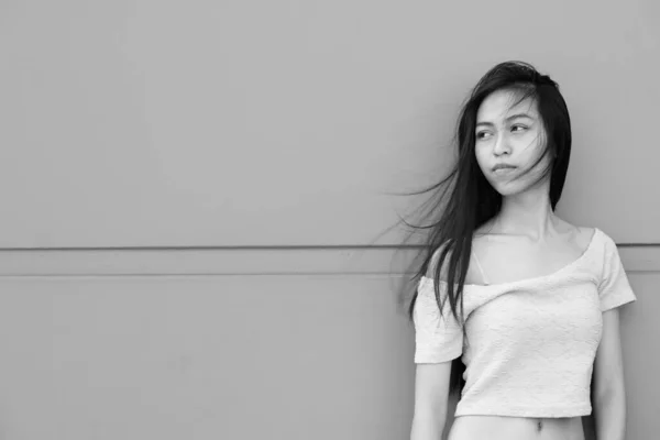 Νεαρή όμορφη Ασιάτισσα έφηβη σκέφτεται ενώ γέρνει προς το τσιμέντο τοίχο σε εξωτερικούς χώρους — Φωτογραφία Αρχείου