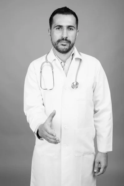 Handsome bearded Persian man doctor against gray background — Stock Photo, Image