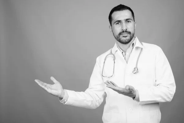 Pohledný vousatý perský muž lékař na šedém pozadí — Stock fotografie