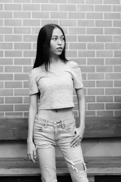 Ung Vacker asiatisk tonårsflicka stående medan tänkande mot tegelvägg — Stockfoto