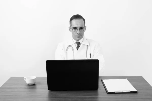 Mature Persian man doctor behind desk in black and white — Stock Photo, Image