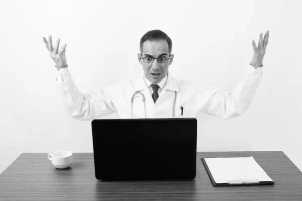 Mature Persian man doctor behind desk in black and white — Stock Photo, Image