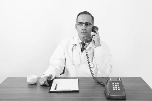 Reife persische Mann Arzt hinter Schreibtisch in schwarz und weiß — Stockfoto