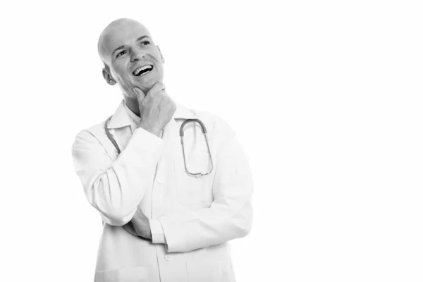 Studio záběr šťastný holohlavý mladík doktor s úsměvem při myšlení — Stock fotografie