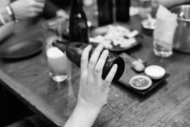 İçki içerek ve takılarak bardağa bira döken adamın eli.