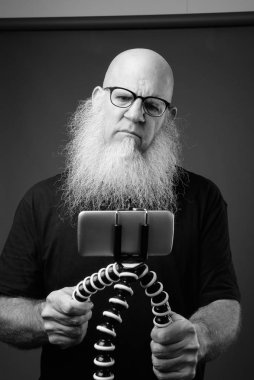 Uzun sakallı, telefonla konuşan olgun kel bir adam.