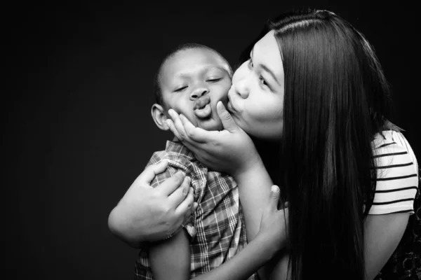 Portrait of mother and son together against black background — ストック写真