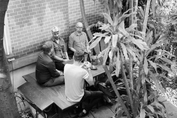 Group of men hanging out and relaxing together in the backyard