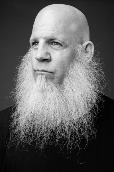 Mature bald man with long white beard in black and white