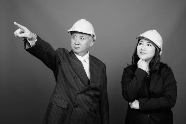 Dojrzałe Azji biznesmen i Dojrzałe Azji businesswoman nosić twardy kapelusz razem — Zdjęcie stockowe