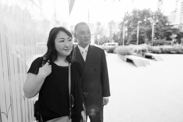 Mature Asian businessman and mature Asian woman exploring the city together