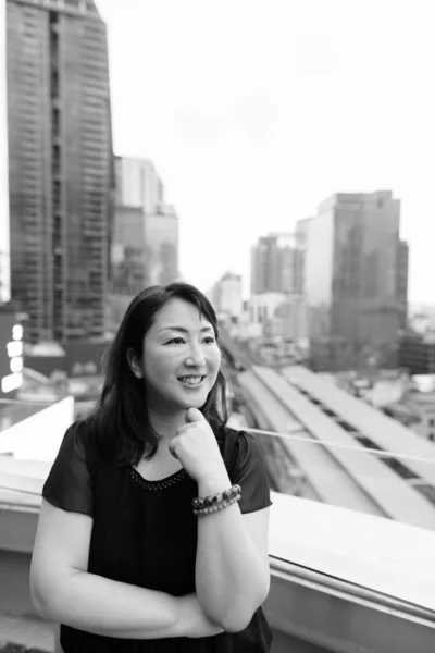 Mature beautiful Asian woman against view of the city